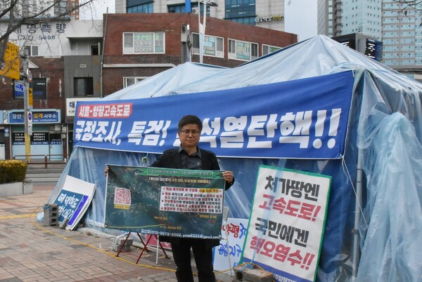 민주당 천막농성장 앞에서 현수막을 들어보이는 김신호씨.